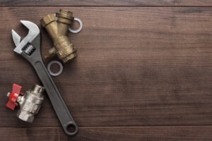 Close-up of a professional heating engineer using an adjustable wrench to repair copper pipes on a central heating boiler system.