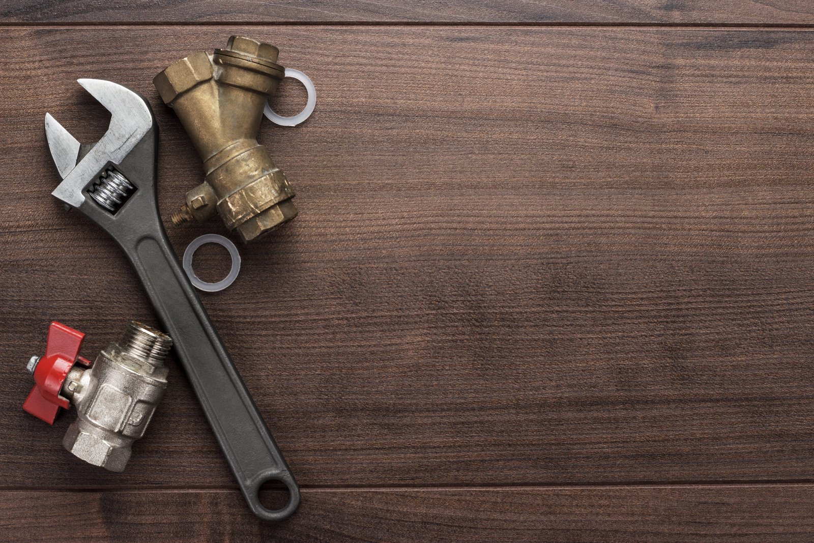 Close-up of a professional heating engineer using an adjustable wrench to repair copper pipes on a central heating boiler system.