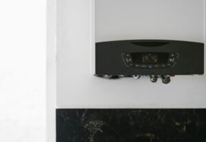 A modern, energy-efficient combi boiler newly installed on a white wall with neat copper pipework underneath.